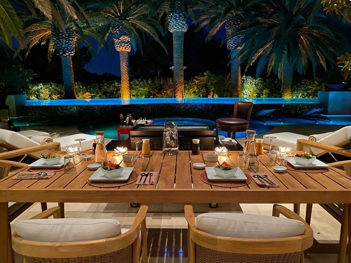 A set Hibachi Hai dinner table at night beside a lit pool and palm trees